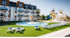 una piscina con sillas y un parque acuático frente a un edificio en Bel Mare 405, en Międzyzdroje