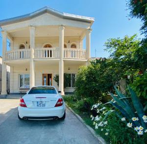 a white car parked in front of a large house at Hotel Elegant in Kutaisi