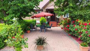 a patio with chairs and an umbrella and flowers at Agroturystyka u Pruszyńskich in Mońki