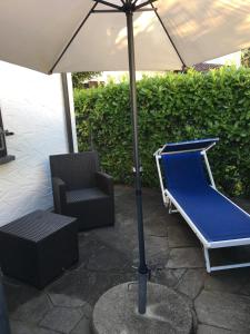 a chair and an umbrella next to a chair and a recliner at Appartamento Via Saleggi 10 in Ascona