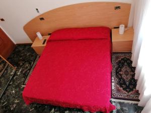 uma cama com uma colcha vermelha num pequeno quarto em Sacco Bed&Breakfast em Rovigo
