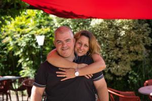 a man hugging a woman under a red umbrella at Hôtel Juantorena in Saint-Étienne-de-Baïgorry