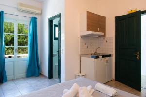 a room with a bed and a kitchen with blue curtains at Almyra Seaside Suites in Platis Gialos +103 photos