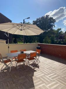 een patio met een tafel en stoelen en een parasol bij Le Jardin Minelle in Arras