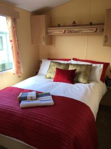 uma cama vermelha e branca com duas toalhas em Ocean Edge Holiday Home em Heysham