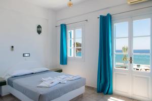 a bedroom with a bed with blue curtains and a window at Almyra Seaside Suites in Platis Gialos