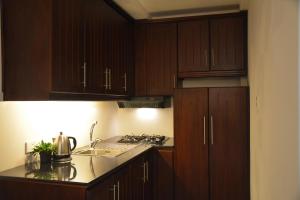 a kitchen with wooden cabinets and a stove top oven at Panoramic Holiday Apartment - Luxury Studio | Nuwara Eliya in Nuwara Eliya