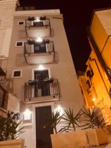 a tall white building with two balconies and plants at Flavì in Bari
