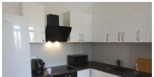 a kitchen with white cabinets and a black microwave at Between Schoenbrunn and the City Center. Apt. 31 in Vienna