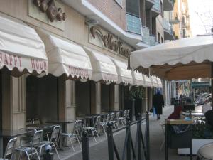 una cafetería con mesas, sillas y sombrillas en una acera en CASA NINO, en Roma