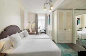 a hotel room with two beds and a chair at Boutique Hotel H10 Villa de la Reina in Madrid