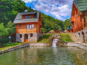 a house in the middle of a pond with a waterfall at Pastravaria Romani in Horezu