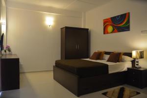 een slaapkamer met een bed en een schilderij aan de muur bij Panoramic Holiday Apartment - Luxury Studio | Nuwara Eliya in Nuwara Eliya