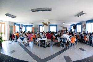 eine Gruppe von Personen, die in einem Restaurant an Tischen sitzen in der Unterkunft L'Arcobaleno in Santa Maria la Palma