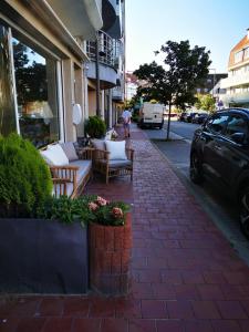 a sidewalk with chairs and tables on a street at Hotel De Backer in Knokke-Heist