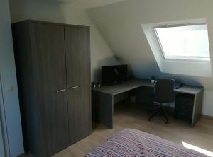 een slaapkamer met een kast, een bureau en een raam bij B&B Lora in Langemark