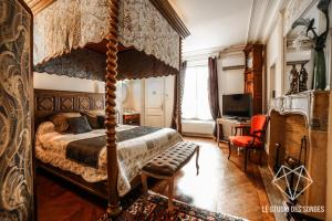 a bedroom with a canopy bed and a desk at Chambre d'hôtes Le Petit Tertre in Dijon