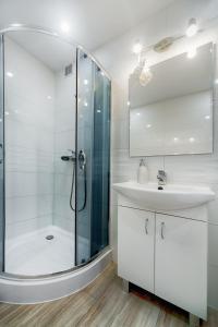 a white bathroom with a shower and a sink at EMI Apartamenty in Świnoujście +12 photos