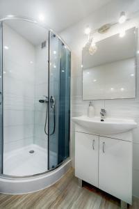 a white bathroom with a shower and a sink at EMI Apartamenty in Świnoujście