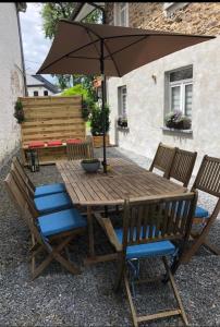 une table en bois avec des chaises et un parasol dans l'établissement Zum Burgblick, à Burg-Reuland