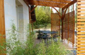 un patio con mesa y sillas bajo una pérgola en Pergoloire, en La Bohalle