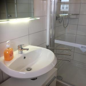 a white bathroom with a sink and a shower at Pension RUBIN in Bremen