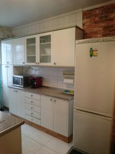 cocina con armarios blancos y nevera blanca en Apartamento Acogedor Bilbao, en Bilbao