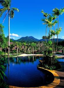 - une piscine avec des palmiers et de l'eau bleue dans l'établissement Annika Koh Chang , Formerly Ramayana Koh Chang Resort & Spa, à Ko Chang