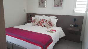 una camera da letto con un grande letto con cuscini rossi e bianchi di Les Jardins des Alizés a Saint-François