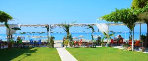 an outdoor patio with tables and chairs and the ocean at Gumuldur Mavi Deniz Hotel in Gumuldur