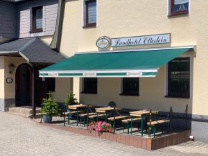 a restaurant with tables and chairs under a green awning at Landhotel Elterlein in Elterlein