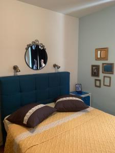 a bed with a blue headboard and a mirror at Rozita Seaside Relax Apartments in Podgora