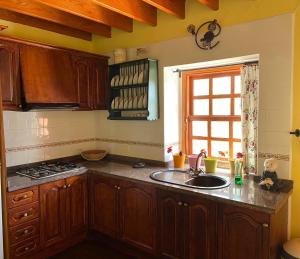 cocina con armarios de madera, fregadero y ventana en CASAS RURALES TIO ANTONIO, en Las Rosas