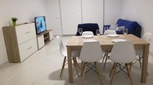 jadalnia z drewnianym stołem i białymi krzesłami w obiekcie Apartamento “El Lometico” w mieście Carboneras