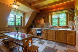 - une cuisine avec des placards en bois, une table et des chaises dans l'établissement Góralski Domek Polaniorka, à Biały Dunajec