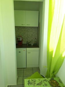 uma pequena cozinha com armários brancos e um lavatório em Rooms and Apartment Stambuk em Split