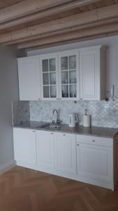 a kitchen with white cabinets and a sink at Apartament Morskie Wzgórze II in Mechelinki