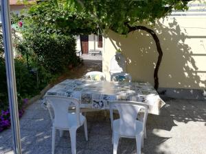 a table with four white chairs and a white table and chairsearcher at La casa di Ginger - Malpensa in Cardano al Campo