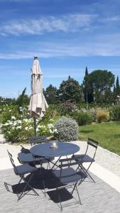 een tafel en stoelen en een parasol en een tafel en stoelen bij Le Cottage du Chat Blanc in Saint-Didier