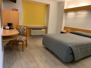 um quarto com uma cama, uma secretária e uma mesa em Intercity Zapopan em Guadalajara