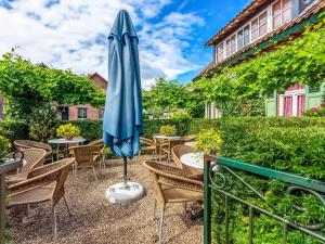 a patio with a blue umbrella and chairs at Holiday Home with Terrace Garden Parking in Uikhoven