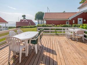 une terrasse en bois avec des tables et des chaises. dans l'établissement 8 person holiday home in Haderslev, à Kelstrup Strand