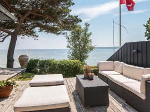 eine Terrasse mit einem Sofa, einem Tisch und Meerblick in der Unterkunft 6 person holiday home in Bjert in Sønder Bjert