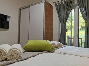 a bed with a green pillow and towels on it at Vila Breza in Soko Banja