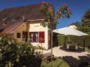 a house with an umbrella and a patio at Beautiful holiday home near the forest in Carsac-Aillac