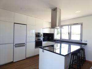 a kitchen with white cabinets and a black counter top at Moradia Faria in Fataca +15 photos