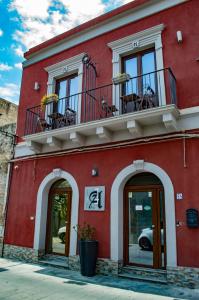 a red building with a balcony and windows at Alterego B&B in Milazzo