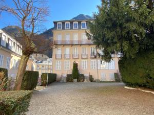 ein großes gelbes Gebäude mit einem Baum davor in der Unterkunft Joli studio rénové au coeur de Cauterets in Cauterets