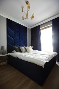 a bedroom with a large bed with a blue headboard at Apartament Navy Residence in Ełk