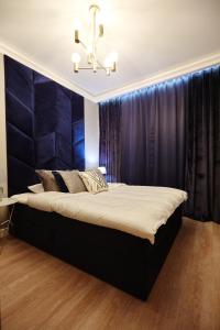 a bedroom with a large bed with a blue wall at Apartament Navy Residence in Ełk